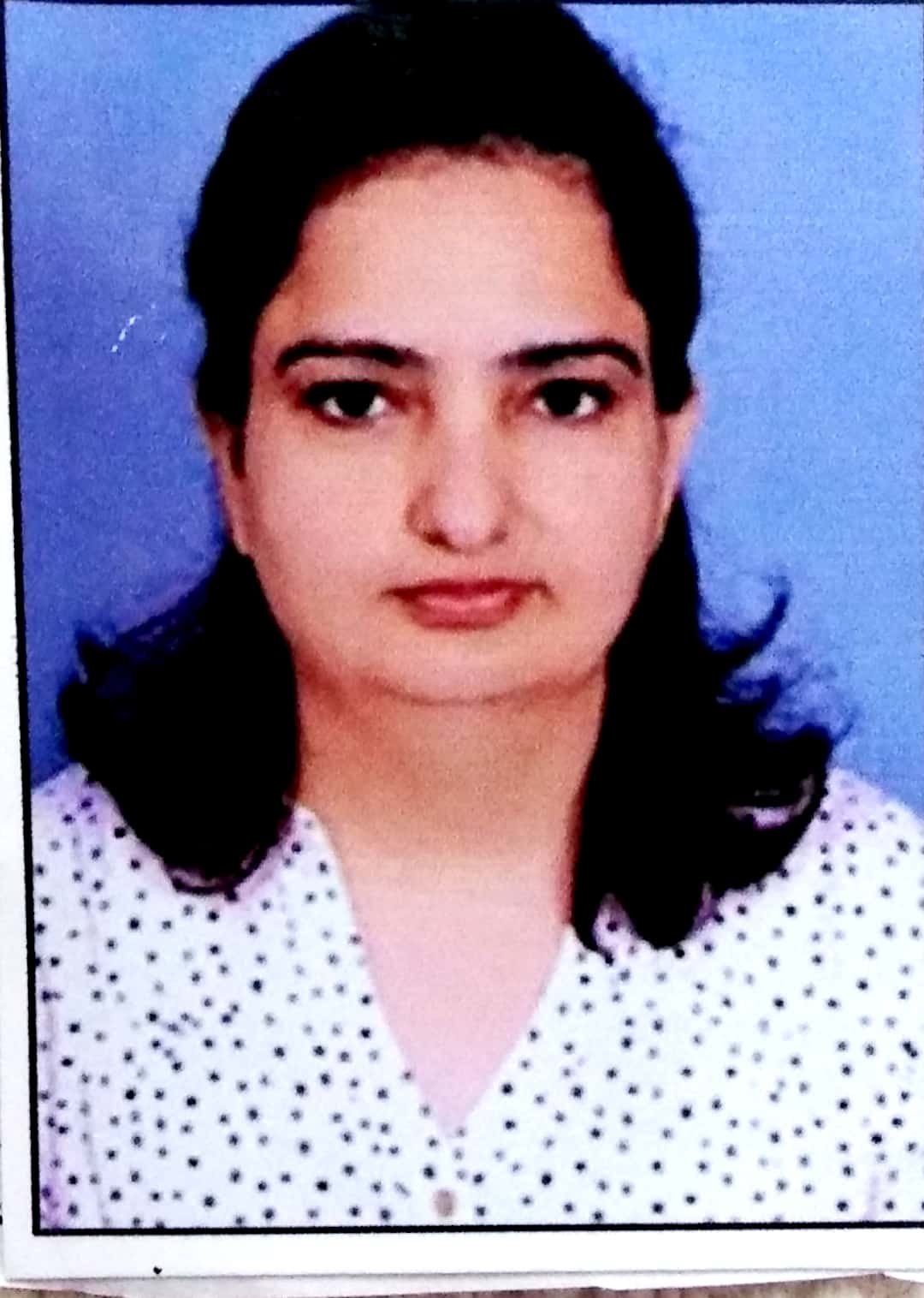 Portrait of Dr. Kapoor wearing traditional attire with academic books in background